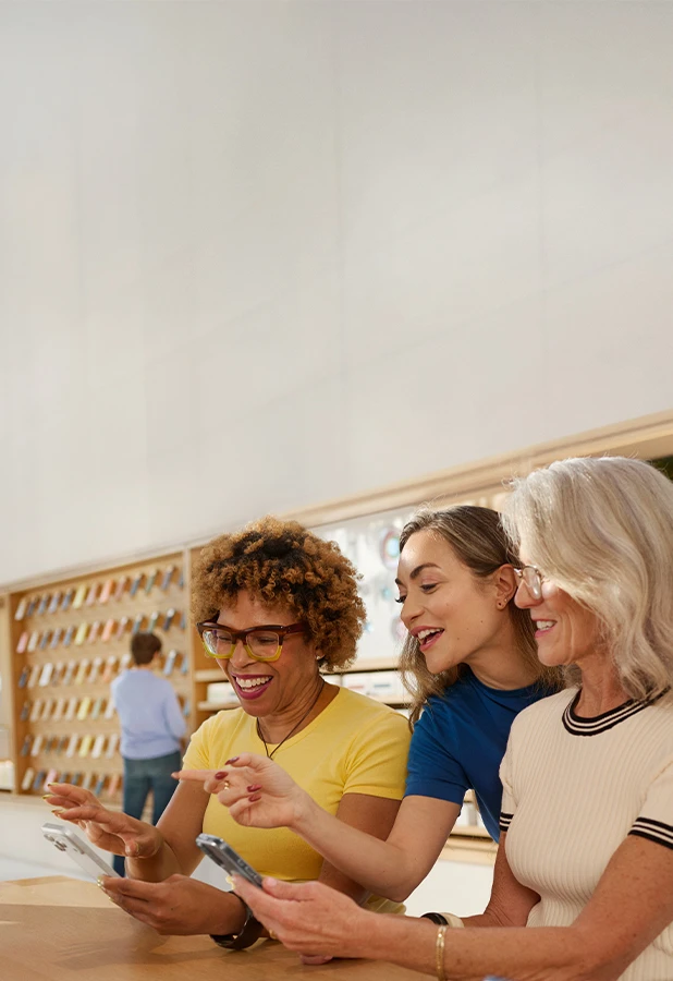An Apple team member helping two customers explore the latest features on iPhone.